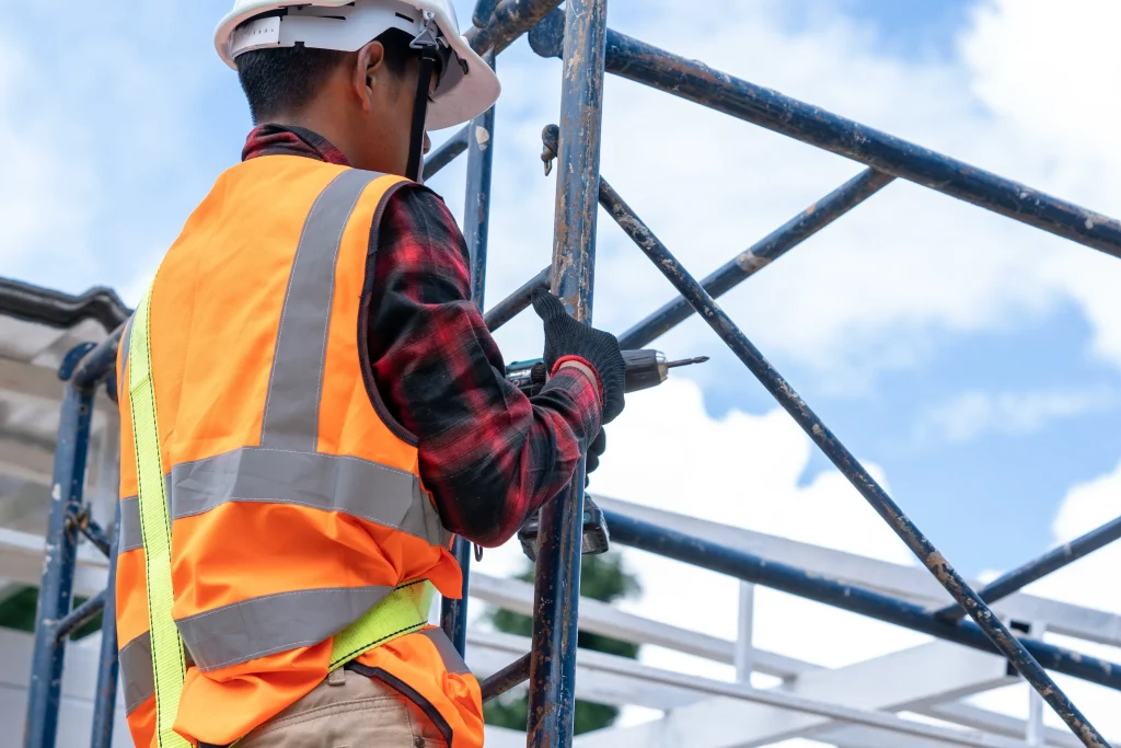 Trabalhadores da construção civil usando cinto de segurança trabalhando em alto nível no canteiro de obras.