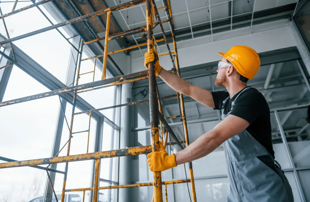 Profissional realizando montagem segura com aluguel rápido de andaimes em ambiente interno.