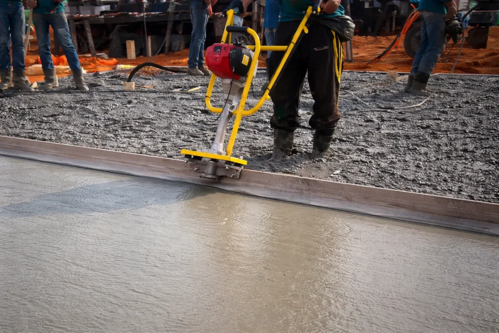 Operador utilizando equipamento no aluguel de régua vibratória para concreto durante nivelamento de piso em obra de grande porte