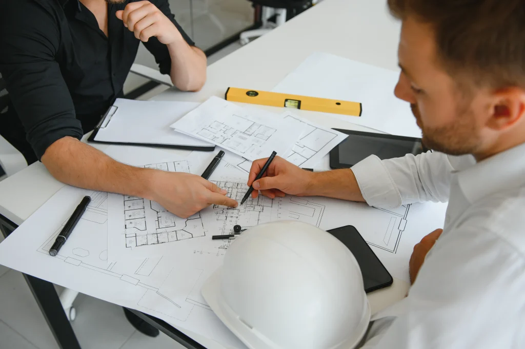 Engenheiros discutindo ajustes e conferindo alinhamento técnico na planta de construção